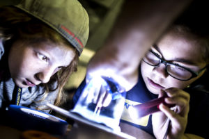Children looking at an electronic with a flash light